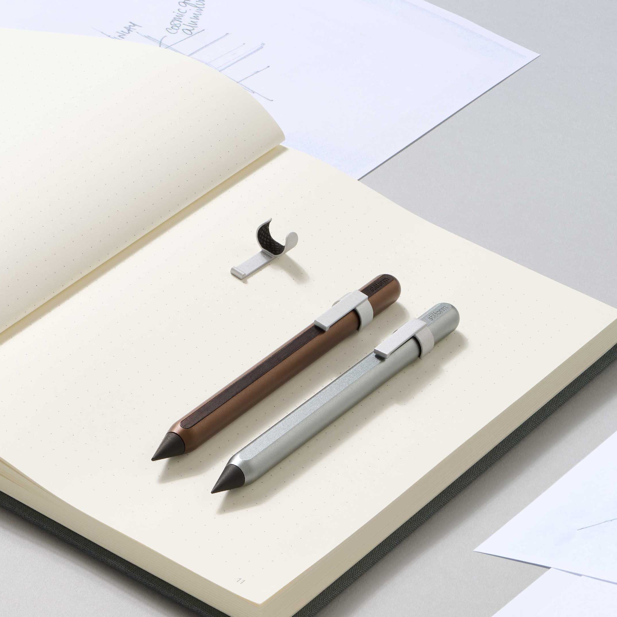 Clip Star Silver mit Bleistift Walnut Brown und Bleistift Pure Star Silver auf geöffnetem Notizbuch